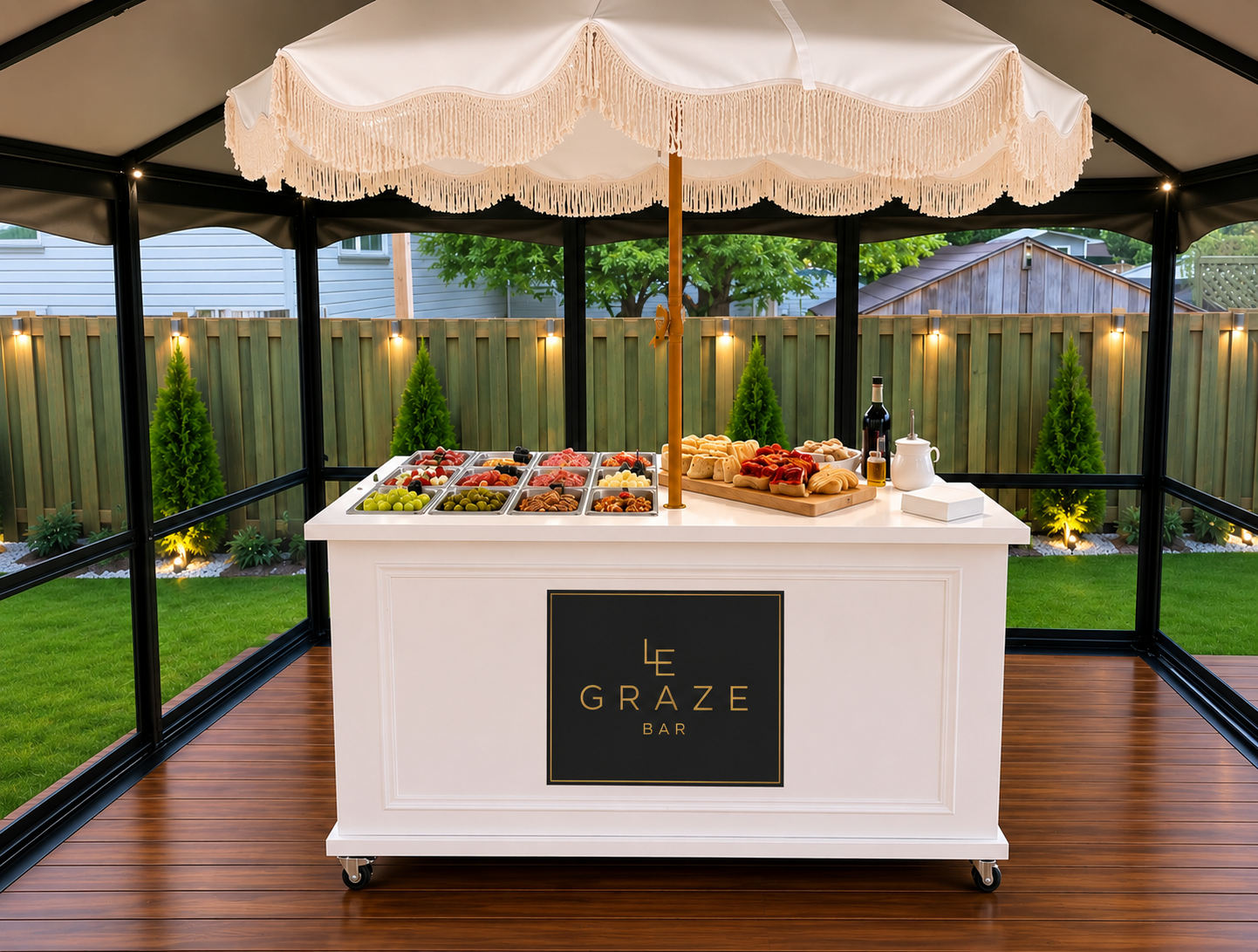 Le Graze Bar signature white charcuterie cart with fringed parasol and gold logo